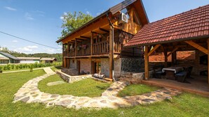 A wooden cabin with a stone foundation, a balcony with flowers, and a stone pathway leading to the entrance. - Amazing home in Veselici with sauna (Veselici)
