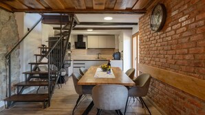 A dining area with a wooden table, four chairs, a clock on the wall, and a staircase leading to a kitchen. - Amazing home in Veselici with sauna (Veselici)