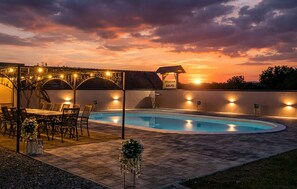 Ein Pool mit Sonnenuntergangsblick, Sitzgelegenheiten im Freien und Lichterketten.