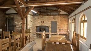 Un interior rústico con paredes de ladrillo visto, una chimenea, muebles de madera y ventanas arqueadas.