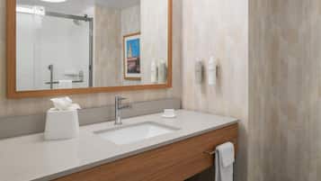 A modern bathroom with a large mirror, a sink, and toiletries.