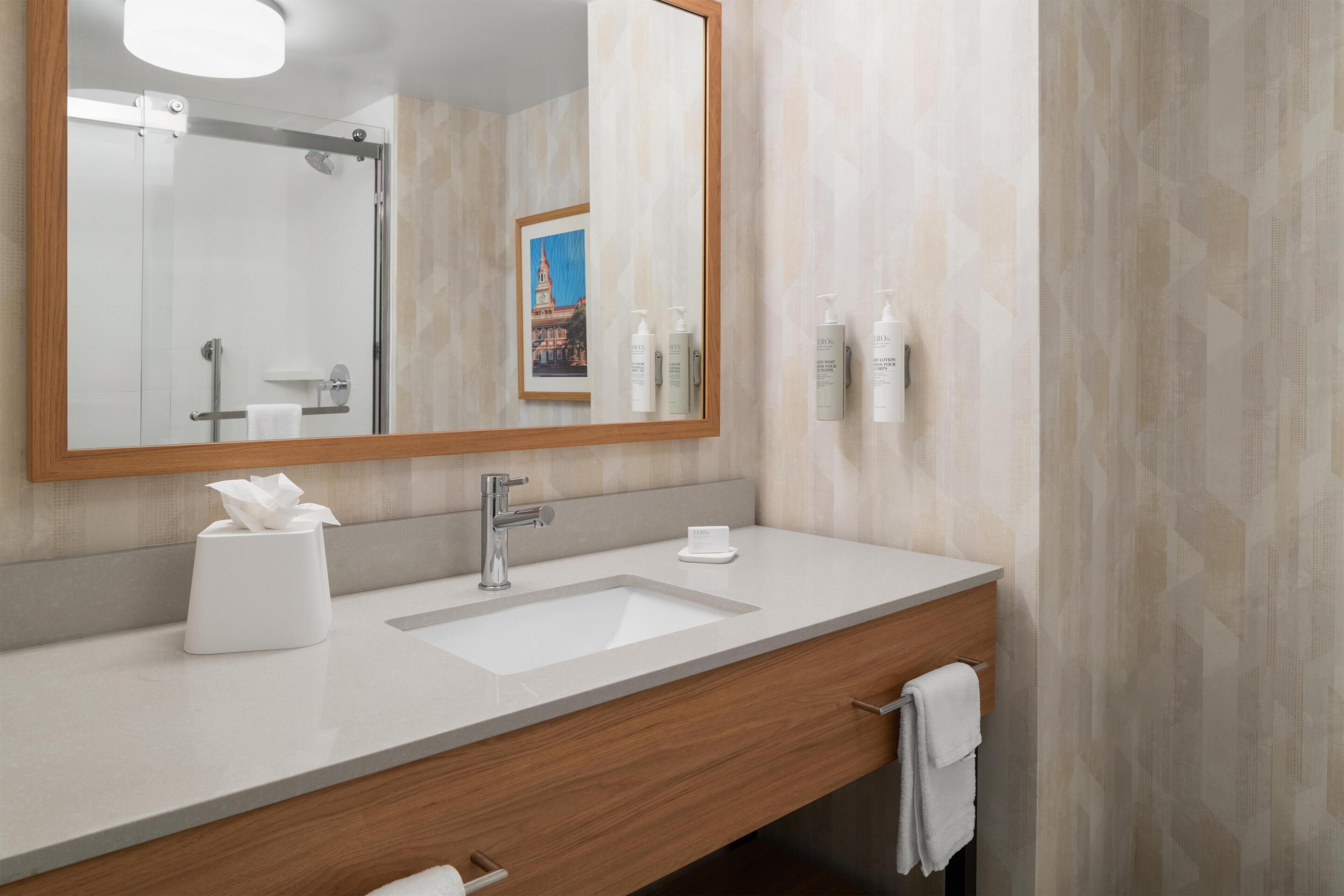 Une salle de bain moderne avec un grand miroir, un lavabo et des articles de toilette.