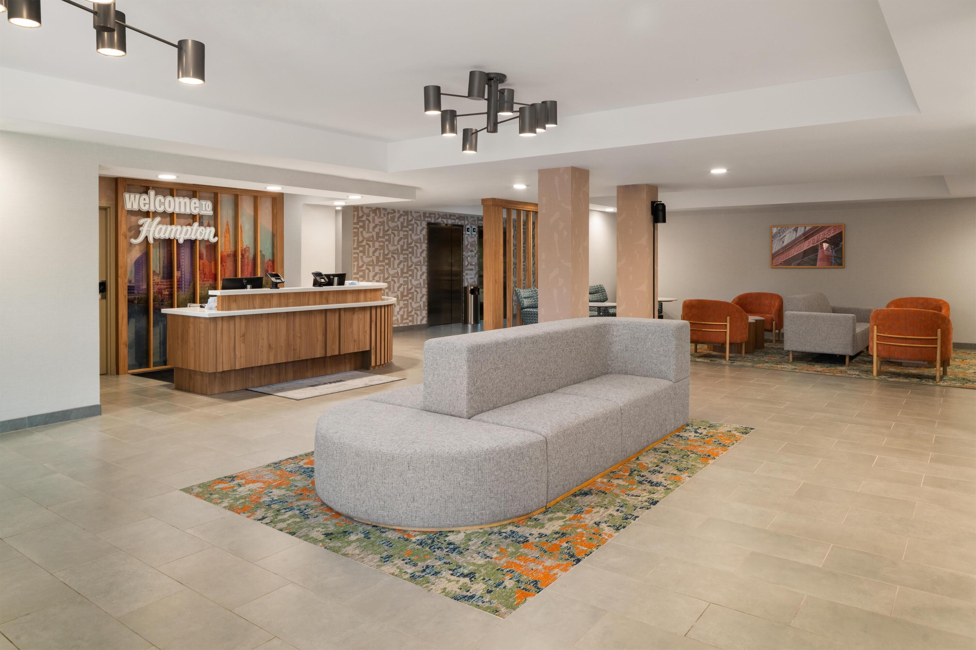 A reception area with a wooden reception desk, a grey sofa, and a colorful rug.