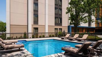 A swimming pool with lounge chairs and a building in the background.