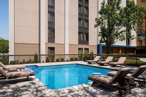 A swimming pool with lounge chairs and a building in the background.