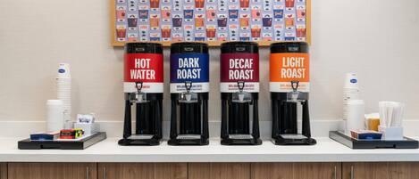 Una estación de café con cuatro dispensadores etiquetados como 'Agua Caliente', 'Tueste Oscuro', 'Tueste Descafeinado' y 'Tueste Claro'.