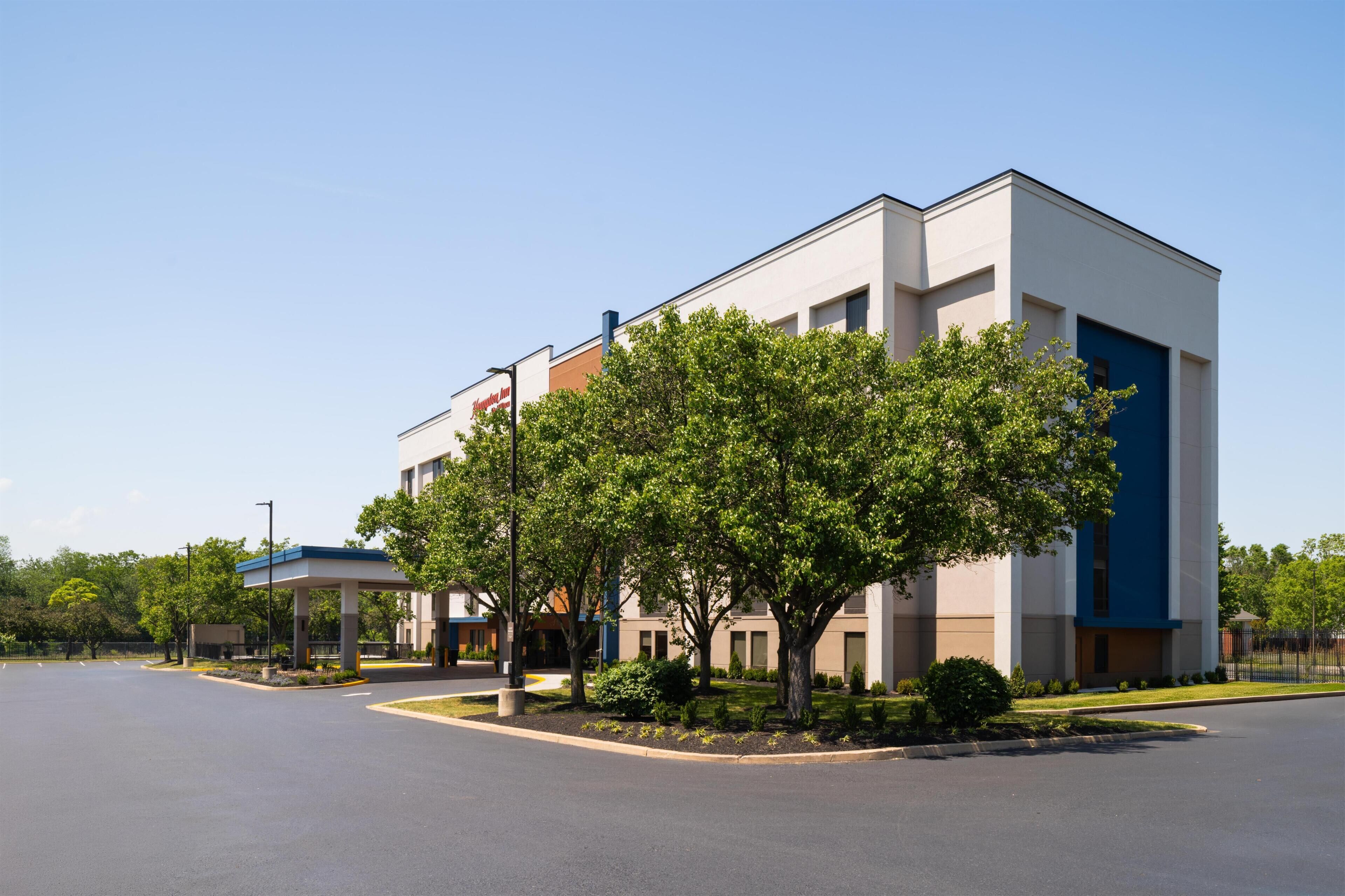 A modern hotel with a central courtyard, a gas station, and a blue building with a sign.