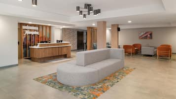 A reception area with a wooden reception desk, a grey sofa, and a colorful rug.