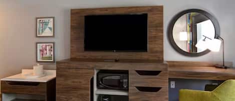 A modern living room with a flat-screen TV, wooden entertainment unit, a round mirror, and a yellow chair.
