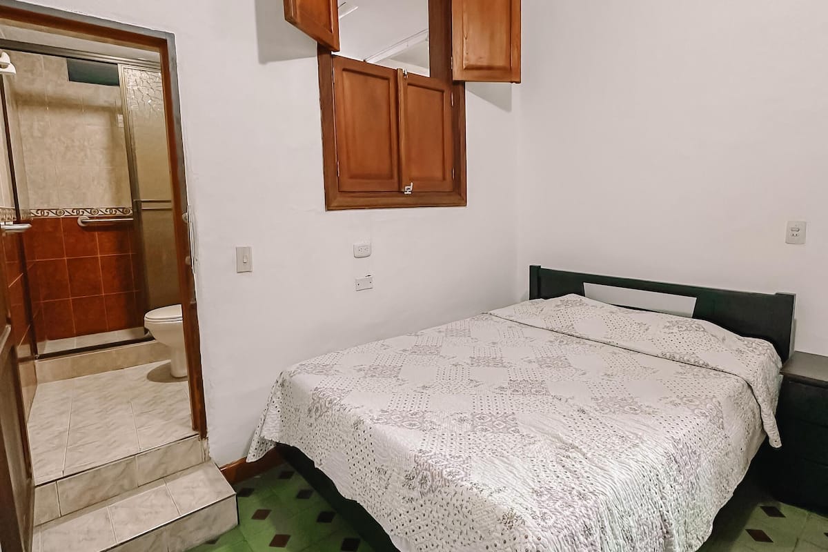 Une chambre à coucher comprenant un lit, une armoire en bois, des toilettes et un escalier.