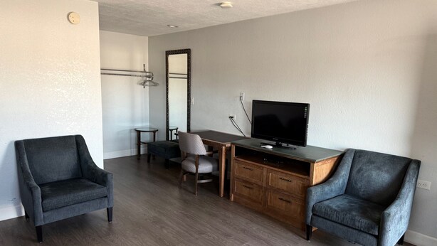 A modern living room with a wooden desk, two armchairs, a television, and a small round table. - WESTERN INN (West Columbia)