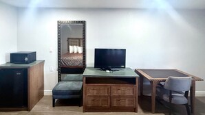 A compact bedroom with a bed, a dresser, a desk, a television, and a chair. - WESTERN INN (West Columbia)