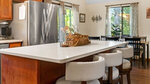 Una cocina con una isla grande, armarios de madera y un refrigerador de acero inoxidable.