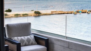A balcony with a chair and a small table, overlooking a beach and water. - Distrito Puerto - Ocean & Mangrove Views (Puerto Morelos)