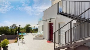 A modern outdoor area with a pool, lounge chairs, and a staircase.