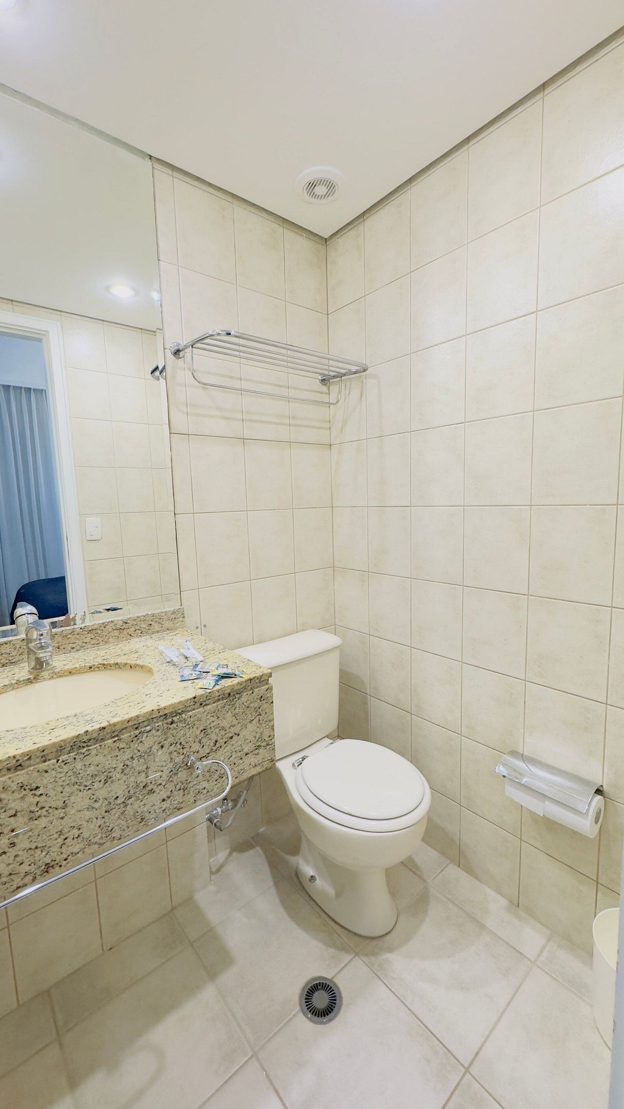 A bathroom with a toilet, sink, and mirror.