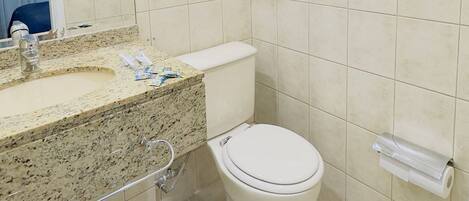 A bathroom with a toilet, sink, and mirror.