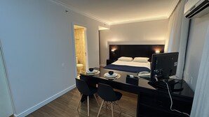 Una habitación de hotel con cama, mesita de noche, escritorio, sillas y una computadora.