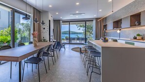 A modern kitchen with a large island, a dining area with a long table and chairs, and a view of the sea through large windows. - Gorgeous home in Medulin with private swimming pool, can be inside or outside (Medulin)