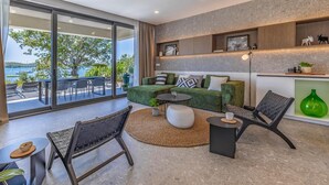 A modern living room with a green sofa, two black chairs, a round coffee table, and a view of the sea through large sliding doors. - Gorgeous home in Medulin with private swimming pool, can be inside or outside (Medulin)