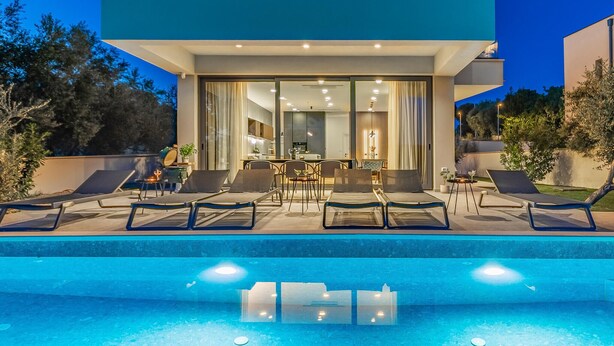 A modern outdoor pool area with lounge chairs and a dining setup. - Gorgeous home in Medulin with private swimming pool, can be inside or outside (Medulin)