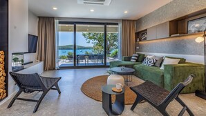 A modern living room with a green sofa, black chairs, a small round table, and a view of the sea through large sliding doors. - Gorgeous home in Medulin with private swimming pool, can be inside or outside (Medulin)