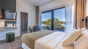 A modern hotel room with a large bed, a seating area with a view, a shower, and a TV.