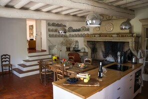 A kitchen with a wooden island, a fireplace, and a variety of dishes on the wall. - Comfort Suite for 4 people (Tarascon)