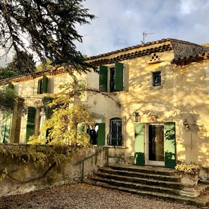 A traditional building with a tiled roof, green shutters, and a stone staircase leading to the entrance. - Comfort Suite for 4 people (Tarascon)