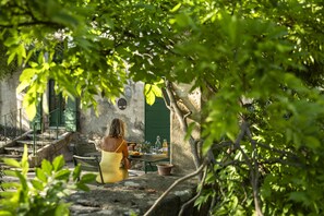 A woman in a yellow dress sitting at a table with a green door in the background. - Comfort Suite for 4 people (Tarascon)