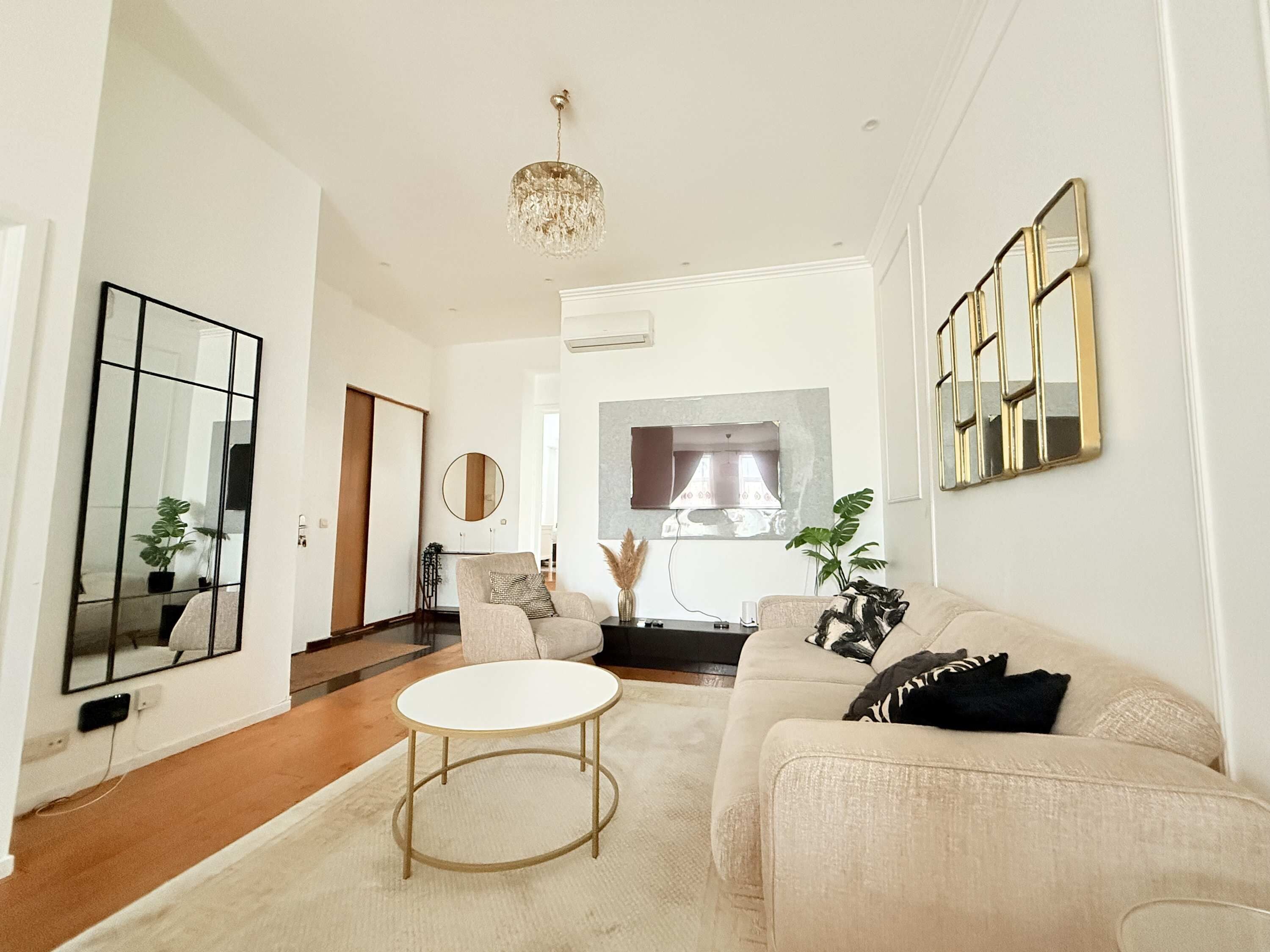 Een moderne woonkamer met een bank, een ronde salontafel en een kroonluchter.