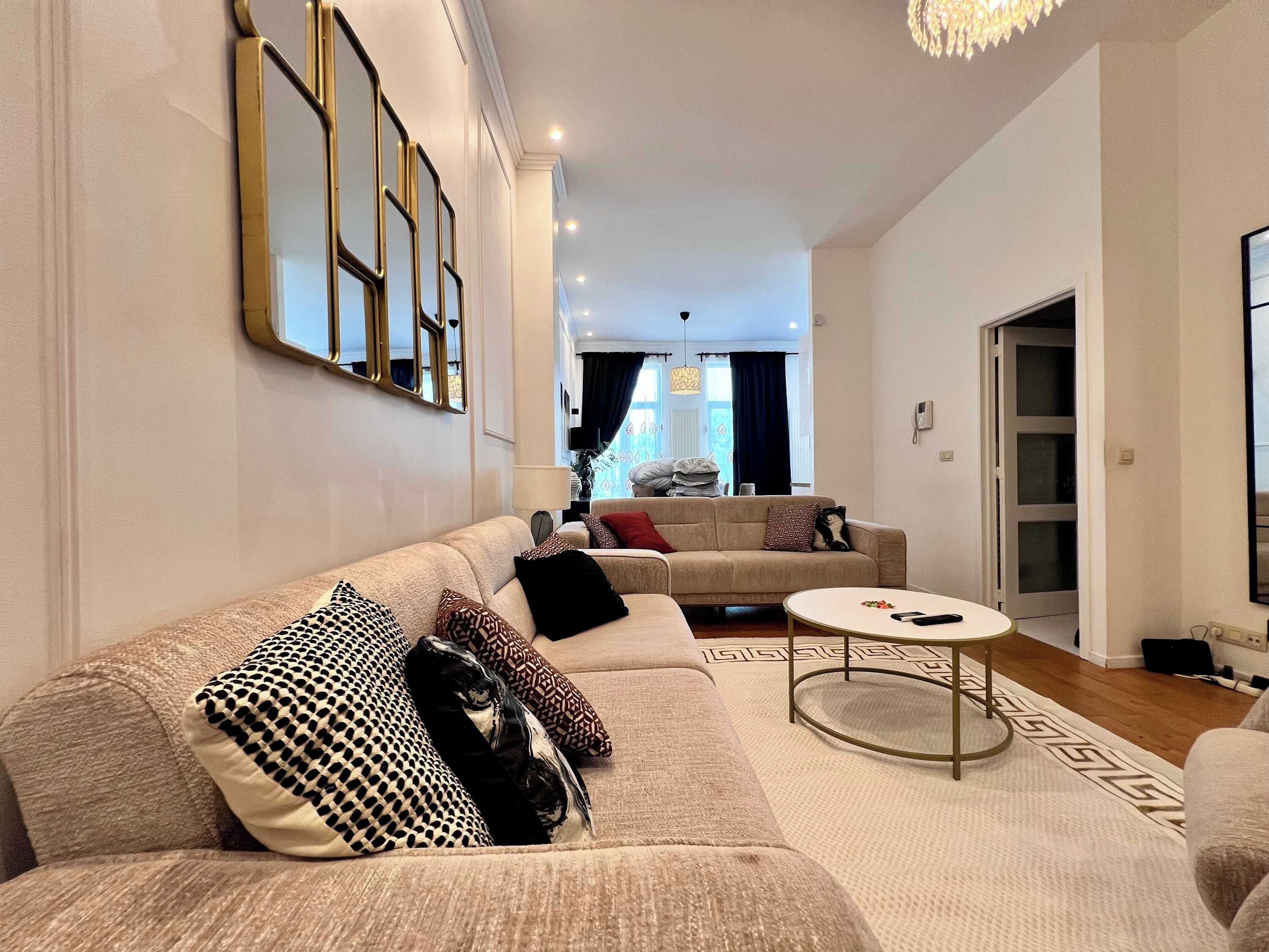 Een moderne woonkamer met een bank, een bijzettafeltje en een vloerkleed met een patroon.