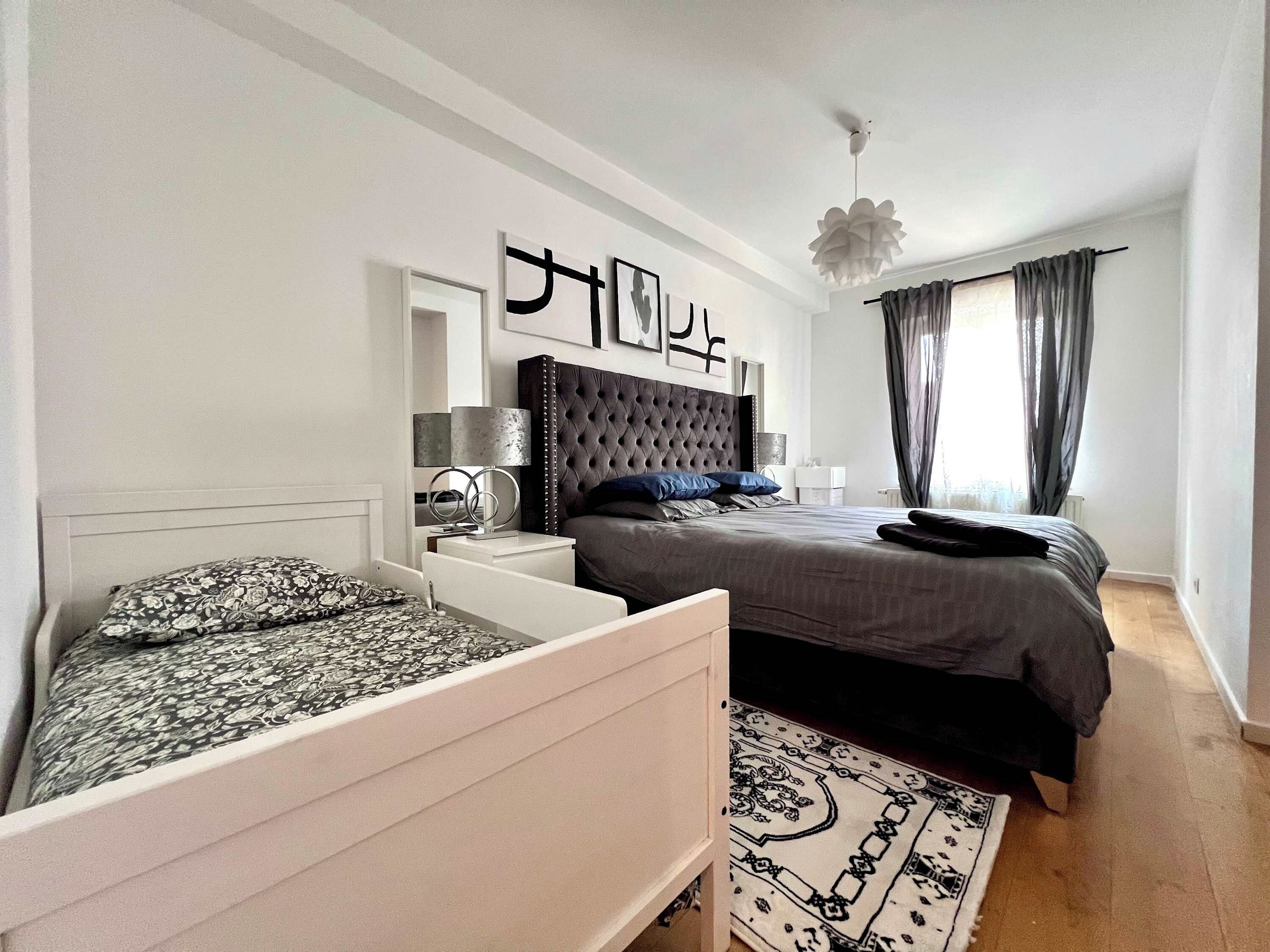 Une chambre à coucher moderne avec un grand lit, des tables de chevet, un miroir décoratif et un luminaire suspendu.