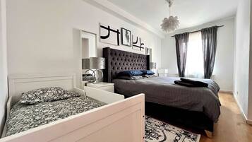 Une chambre à coucher moderne avec un grand lit, des tables de chevet, un miroir décoratif et un luminaire suspendu.