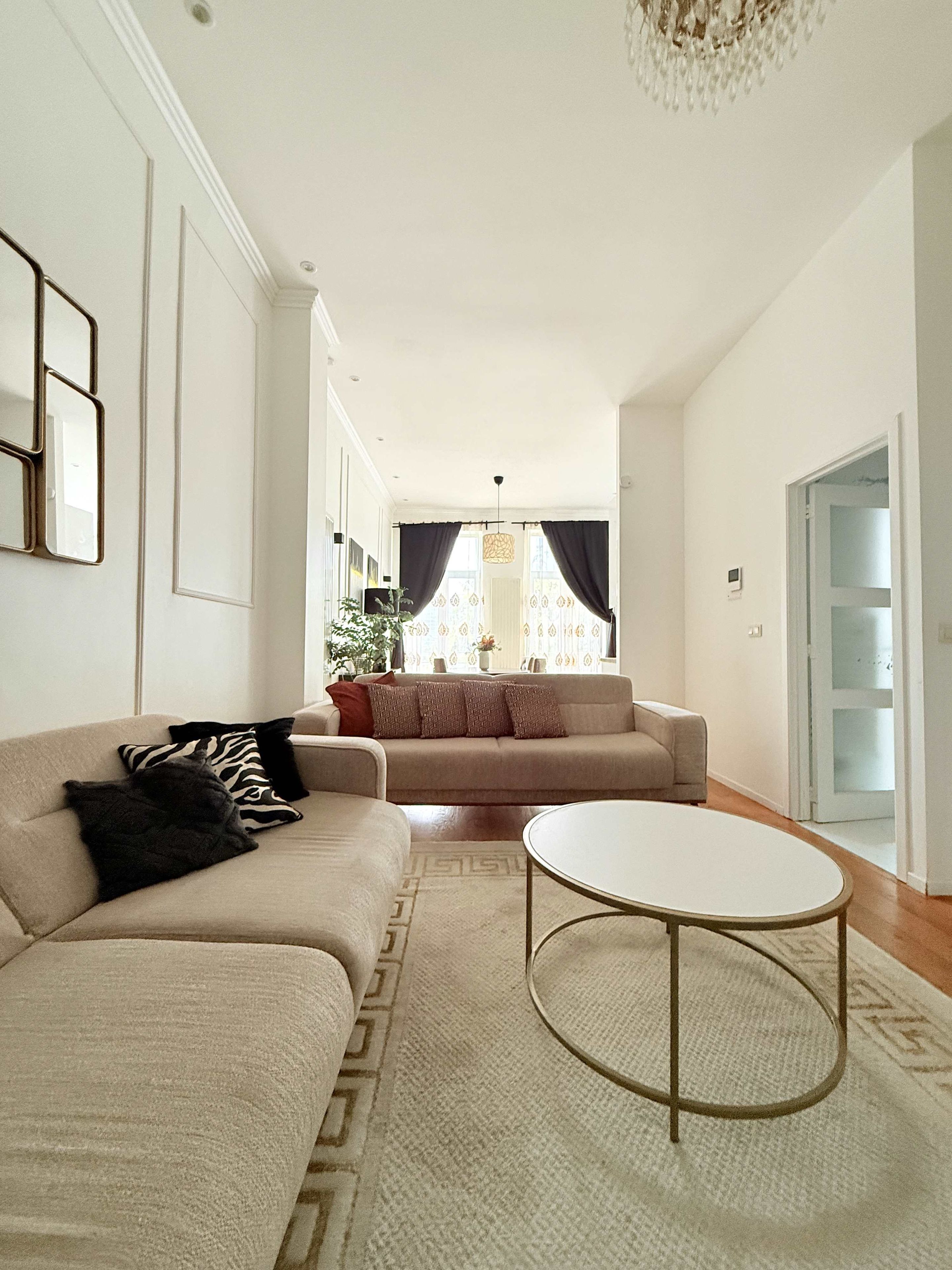 A living room with a sofa, a coffee table, and a chandelier.