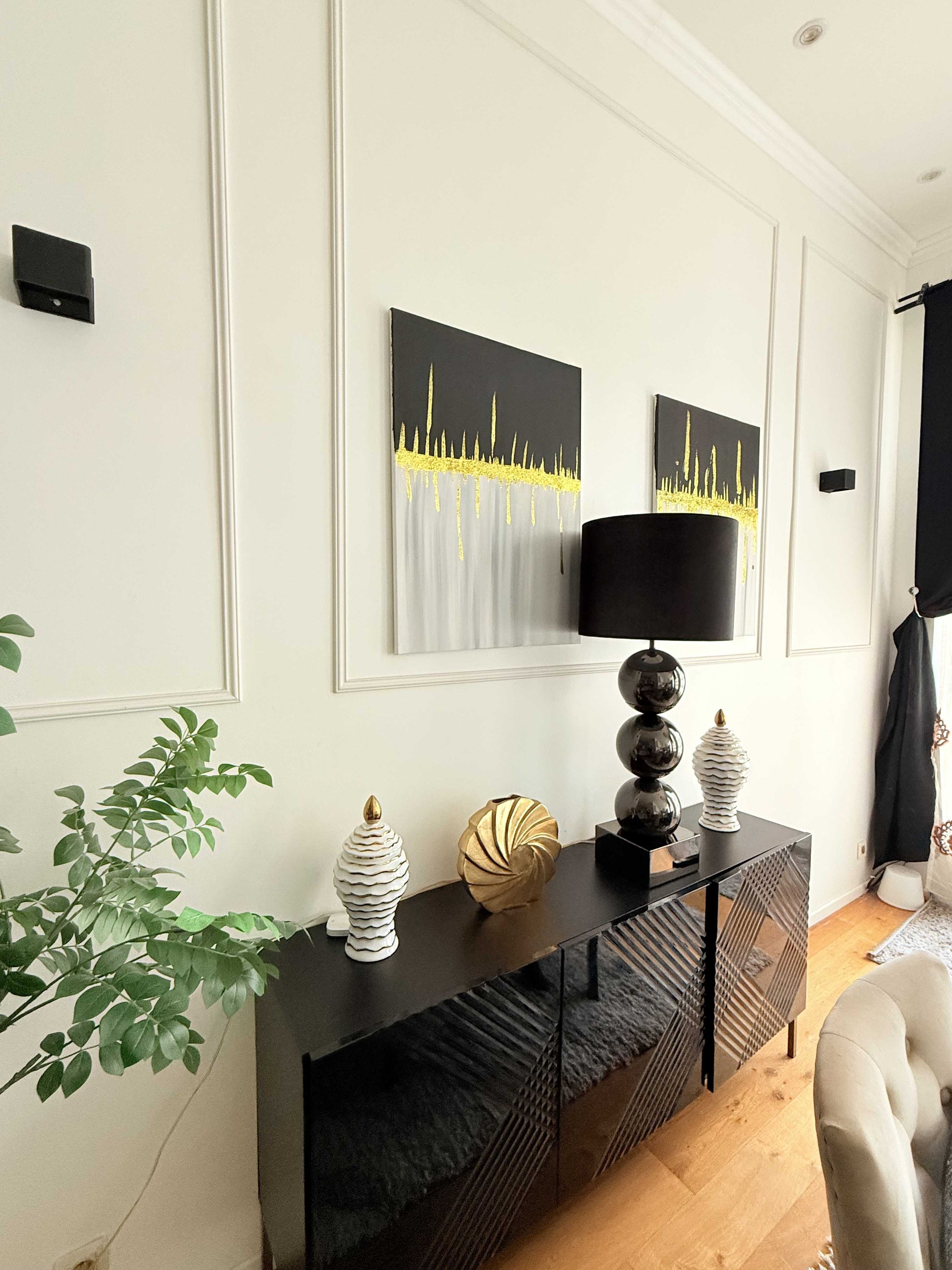 A modern living room with a black console table, decorative vases, and two abstract paintings on the wall.