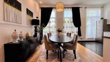 Un espace repas moderne avec une table ronde, des chaises, une console noire et un vase décoratif.
