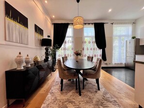A modern dining area with a round table, chairs, a black console, and a decorative vase.