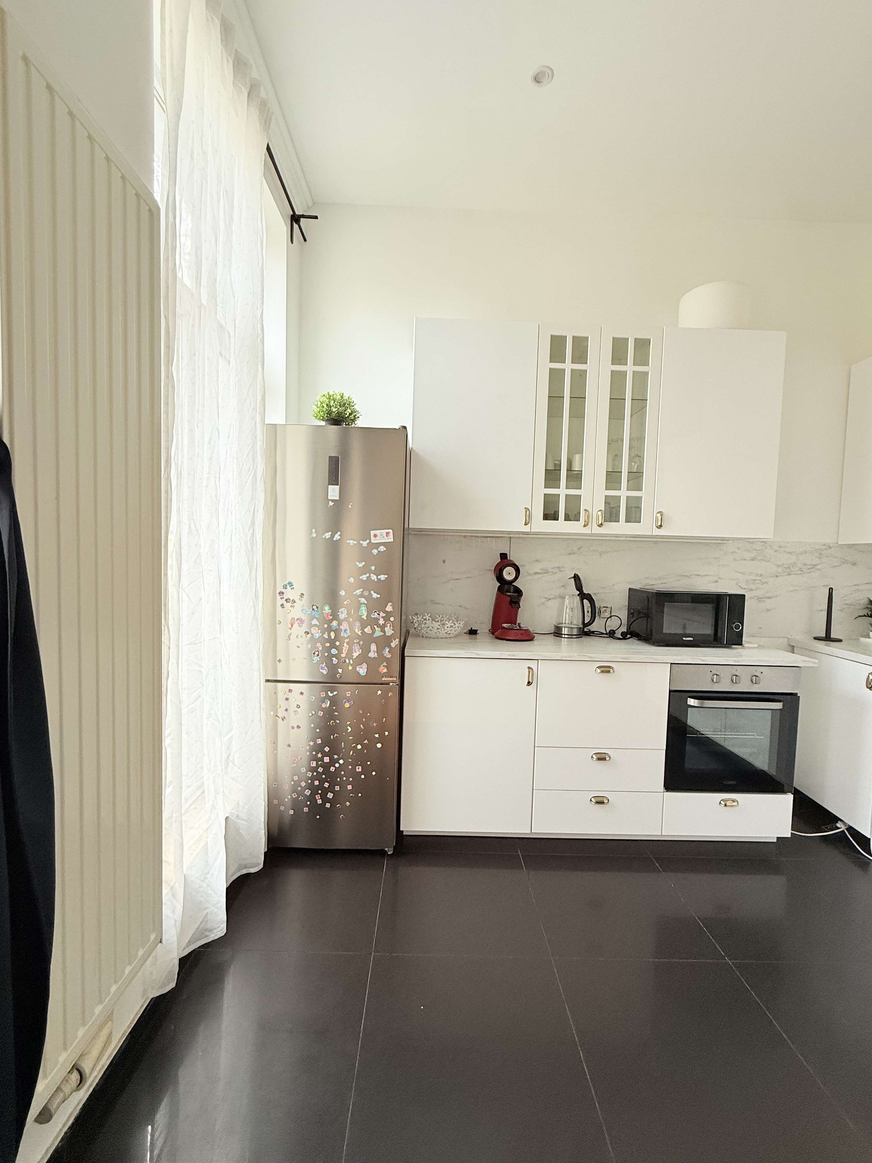 Een moderne keuken met witte kasten, een roestvrijstalen koelkast, een magnetron en een oven.