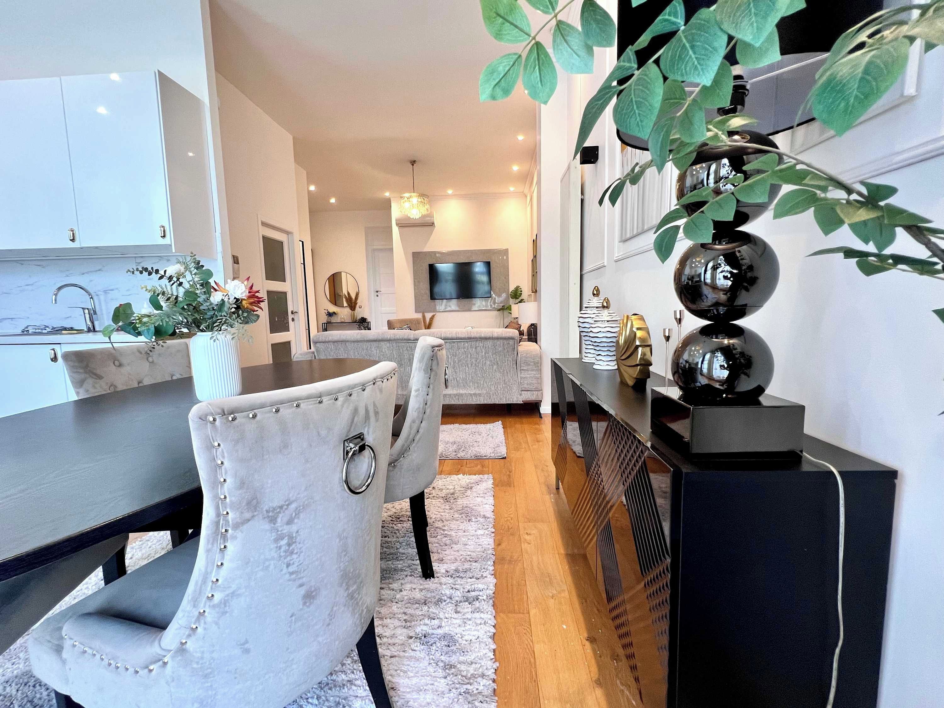 Une cuisine moderne avec un coin repas, un téléviseur fixé au mur et une plante décorative.