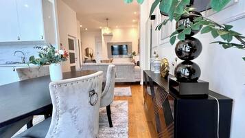 Une cuisine moderne avec un coin repas, un téléviseur fixé au mur et une plante décorative.