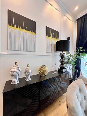 A modern living room with a black console table, two white decorative vases, a gold-colored vase, and a black lamp.