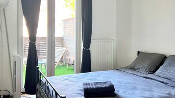 Une chambre à coucher avec un lit, des rideaux, un radiateur et une vue sur l’extérieur.