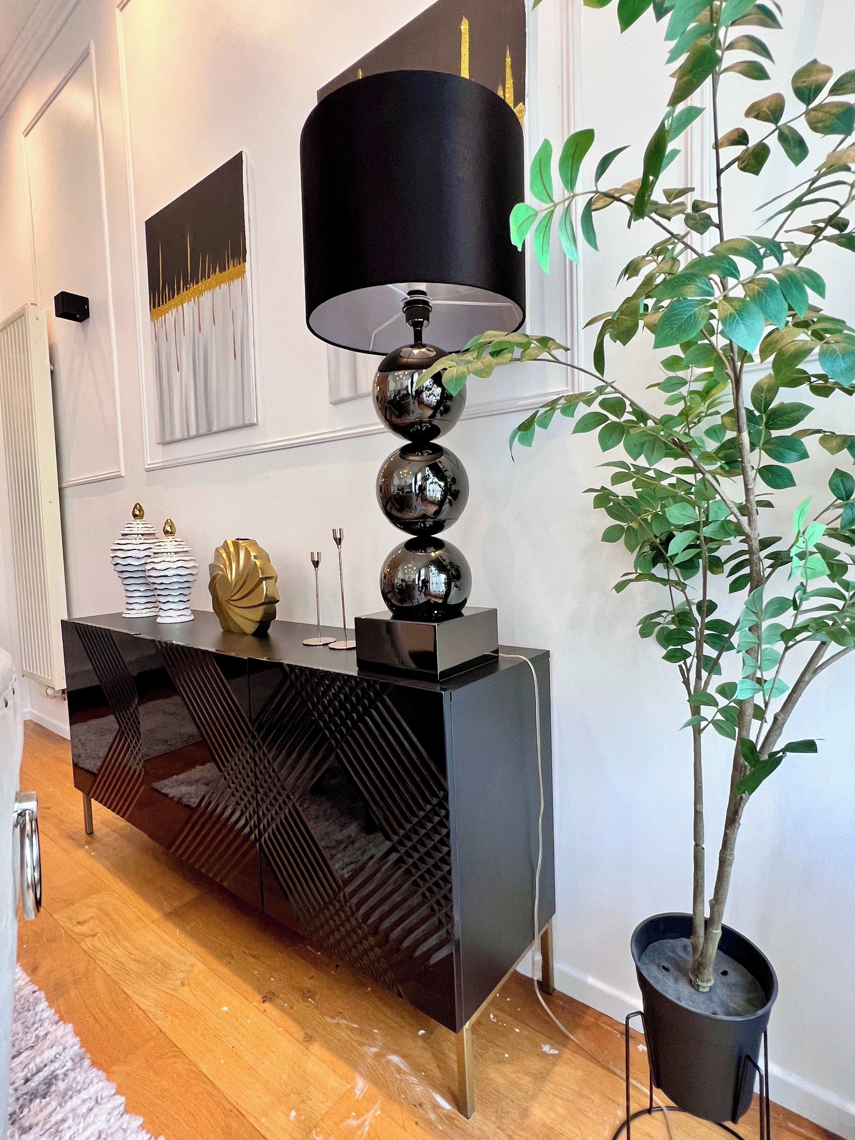 Een modern interieur met een zwarte console tafel, een potplant en een wandlamp.