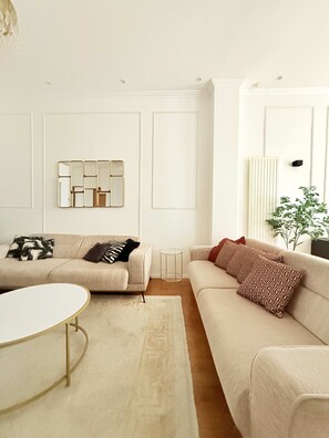 Ein modernes Wohnzimmer mit zwei Sofas, einem Couchtisch und einem dekorativen Spiegel.