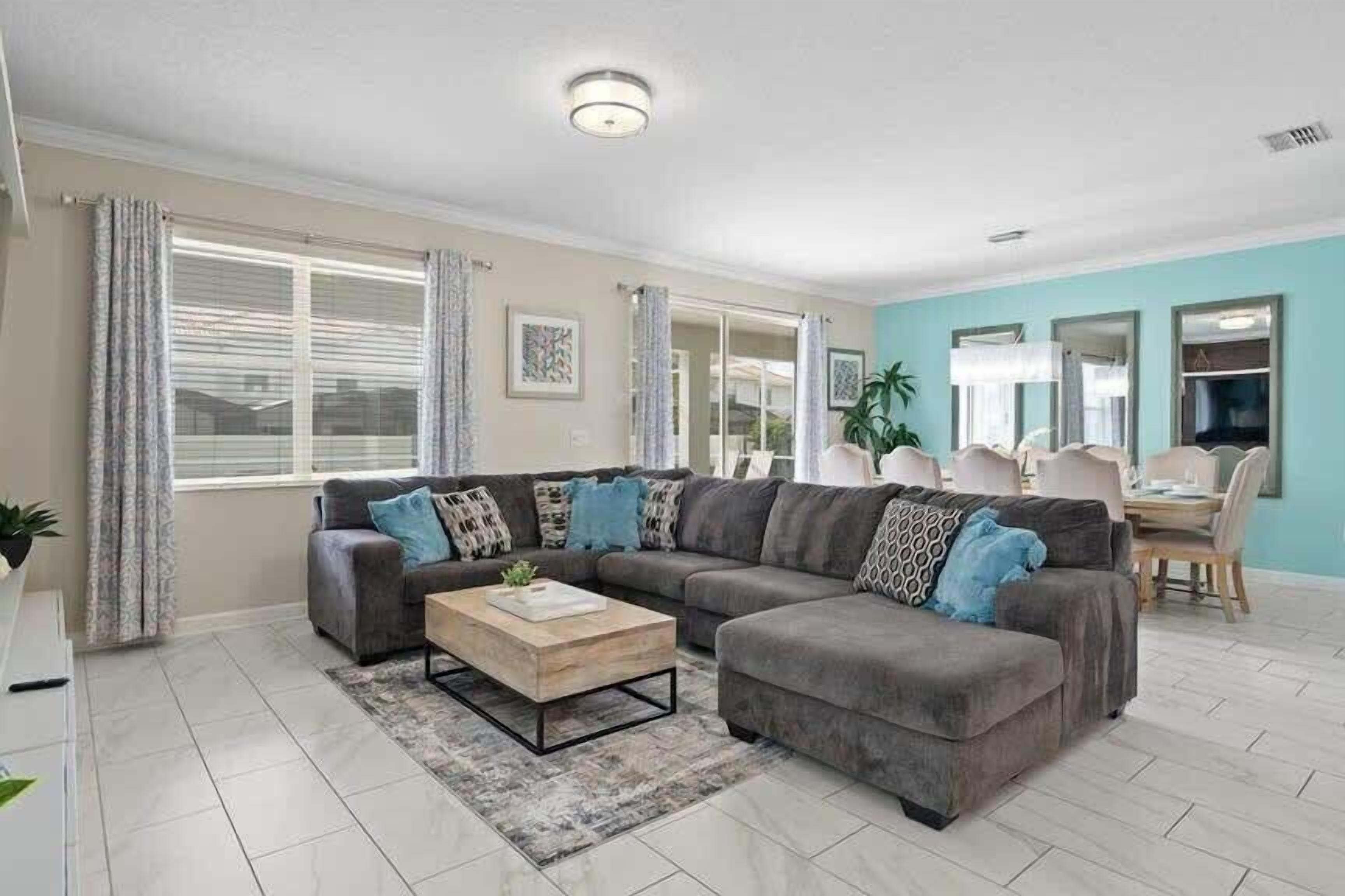 A modern living room with a sectional sofa, a coffee table, and a dining area with chairs and a table.
