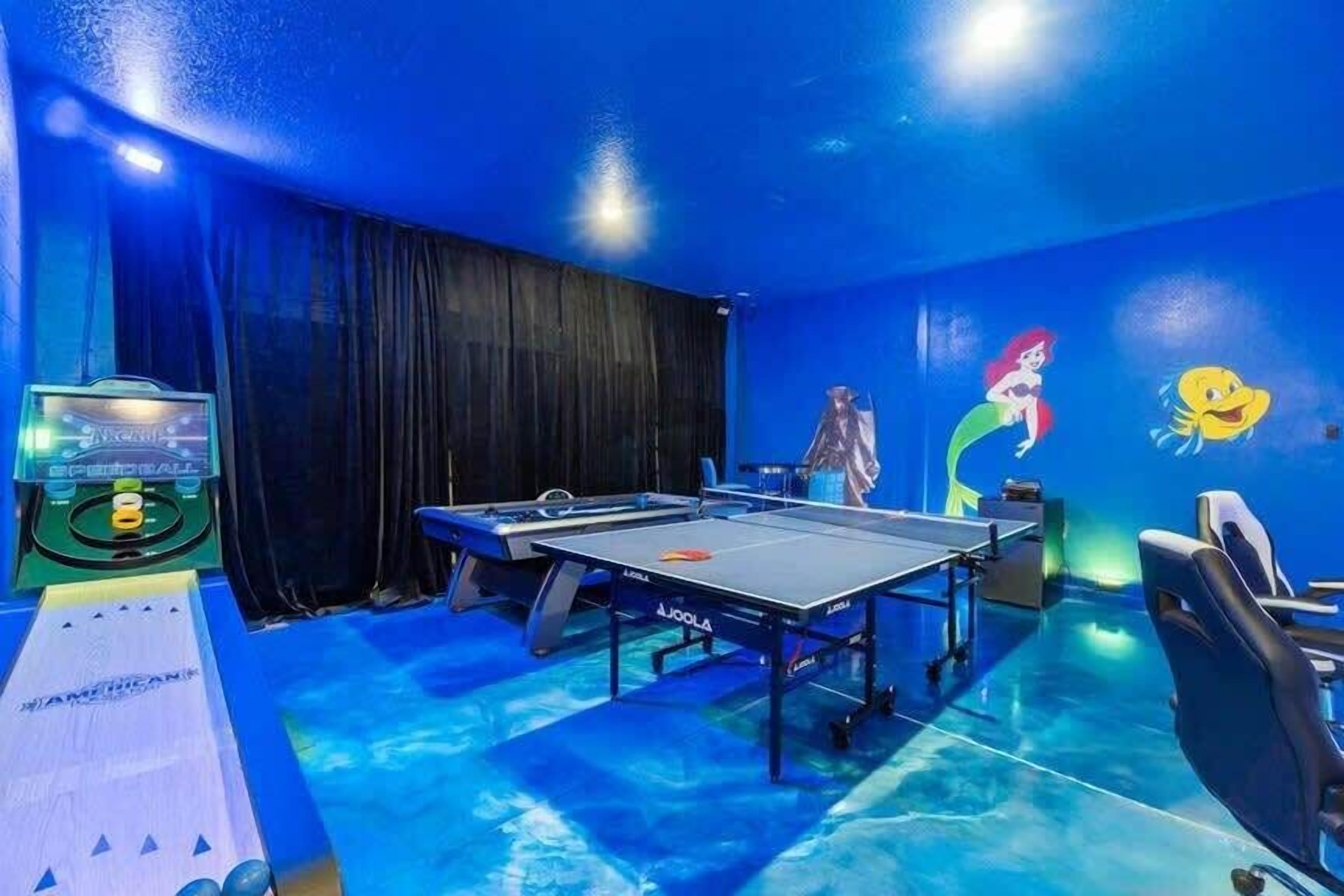 Ein Raum mit Tischtennisplatte, Billardtisch und Dartscheibe.