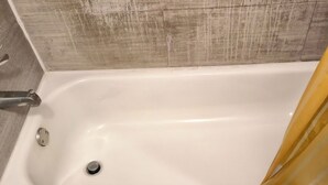 Eine Badewanne mit Duschvorhang, Wasserhahn und Ablass.