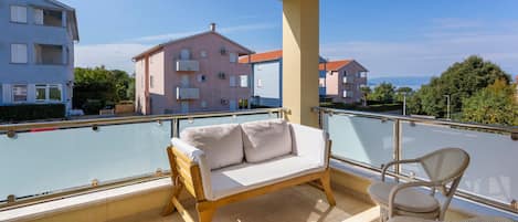 Een balkon met een bank en stoelen, met uitzicht op een woongebied met gebouwen.