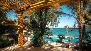 A beach view with a wooden pergola, palm trees, and a clear blue ocean. - Corrales Bay Resort (Los Corrales)